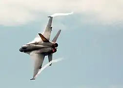 F/A-18C laissant des traînées de condensation dans les parties de basse pression des tourbillons aux extrémités de ces ailes.