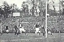 Photo noir et blanc d'un but marqué dans le petit filet, hors de portée du gardien lors d'un match de football.