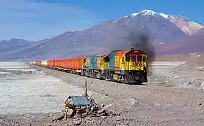 Un train du FCAB tracté par trois locomotives diesel EMD traverse le Salar de Acostan sur la ligne qui relie Ollagüe à Calama. En arrière-plan le stratovolcan "Cerro del Azufre" qui culmine à 5846 mètres.