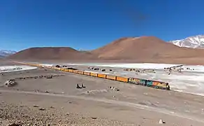 Train vide près de l'établissement de Cebollar, en bordure du salar d'Ascotan. Ce train est utilisé pour le transport de vrac de minerai d'argent entre la mine de San Cristóbal et Mejillones. Juillet 2013.