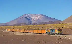 Un train, probablement chargé de minerai d'argent, de la Mine de San Cristóbal au port d'Antofagasta. À l'arrière plan le volcan Cerro Ascotan. Juillet 2013.