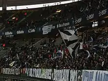 Photo d'une tribune haute remplie de supporters ultras pendant un match.