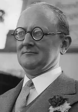 Photographie (portrait) en noir et blanc d'un homme portant des lunettes.