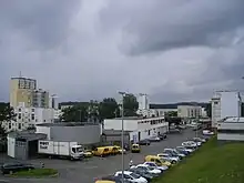 Photo d'un parking avec des bâtiments en arrière plan.