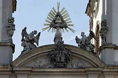Détail de la façade montrant les armoiries de Buda sous le symbole de la Trinité encadré de deux anges