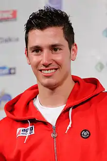 Homme, portant une veste à capuche rouge, souriant