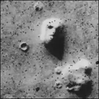 Photo satellite d’un rocher sur Mars, dont les ombres créent le visage de Mars.