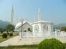 Petit mausolée blanc devant une mosquée de marbre blanc