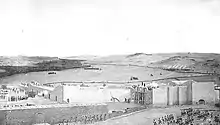 Complexe de bâtiments avec des murs bas situé dans un paysage vallonné