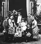 Photographie en noir et blanc d'un groupe de sept enfants et adolescents avec leurs parents.