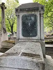 Photographie d'une tombe en pierre et en bronze.