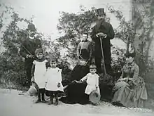Famille posant avec parents et enfants, tous en tenue du XIXe siècle.