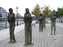 6 statues de bronze, plus grandes que nature, quatre hommes dont un porte un enfant, deux femmes, décharnés, hébétés, en haillons