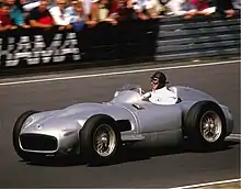 Photo de Juan Manuel Fangio pilotant en 1986 la Mercedes-Benz W196 des saisons 1954 et 1955.