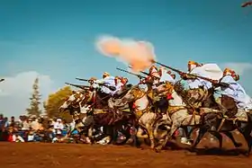 Groupe de cavaliers photographiés au moment du tir de la salve de fusils.