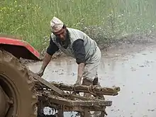 Homme travaillant sous la pluie derrière un tracteur