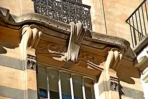 Couronnement d'une fenêtre du premier étage : consoles en pierre blanche, larmier et fleuron en pierre bleue