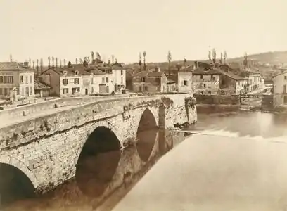 Vue en noir et blanc d'un pont à trois arches sur un cours d'eau, une ville vallonée en arrière-plan.