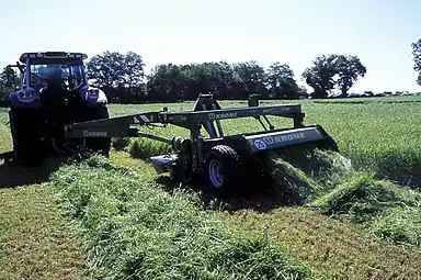 Faucheuse-conditionneuse au travail, la conditionneuse secoue ou écrase le fourrage pour accélérer sa dessication.