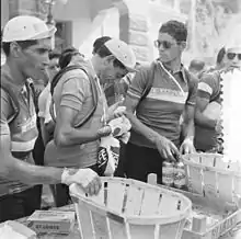 Fausto Coppi, entouré de Giovanni Corrieri et Mario Baroni, mange une orange durant le Tour de France 1952