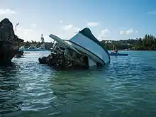 A small, upended yacht resting on a rock