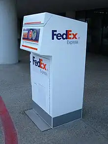 Photographie couleur d'une borne conteneur blanche de la marque FedEx.
