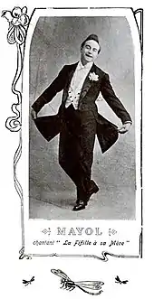 Photographie en médaillon d'un chanteur en costume, prenant une pose, l'image étant sous-titrée et entourée d'une bordure à motif végétal.