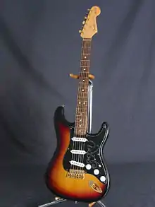 Photographie d'une guitare Fender stratocaster signée Stevie Ray Vaughan, sur un porte-guitare.