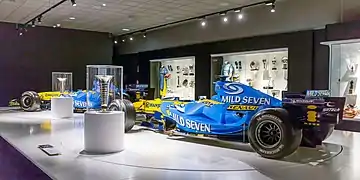 Les Renault R25 et R26 des deux sacres en 2005 et 2006, accompagnées des deux trophées de champion du monde de Formule 1.