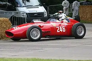 Photographie en couleur d'une Ferrari Dino rouge, vue de profil, en piste.