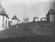 Photographie en noir et blanc de mauvaise qualité représentant la montée du chemin du Calvaire, avec les chapelles tout du long.