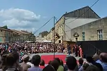 Photographie d'un spectacle en plein-air entouré d'une foule.