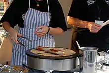 Deux galettes-saucisses en préparation sur une crêpière.