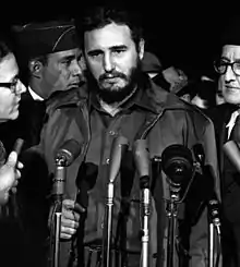 Photographie en noir & blanc de Fidel Castro, face à des micros