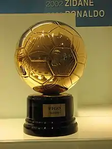 Portrait d'un trophée dorée en forme de ballon avec un support noir