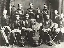 Photographie en noir et blanc d'une équipe de hockey sur glace avec trois joueurs debouts et sept autres assis devant