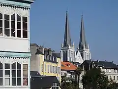 Photographie en couleurs des deux flèches d'une église dépassant au-dessus des toits.