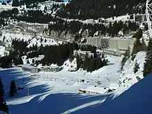Station de ski enneigée. On y distingue des remonte-pistes, des skieurs, et des bâtiments.