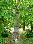 Vue d'une croix en pierre sous un arbre.