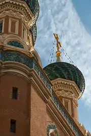 Vue en contre-plongée de la croix au sommet d'une tour d'une cathédrale orthodoxe russe à mur rouge et toiture bleue.