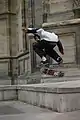 Un skater effectue un flip. Il est en l'air et a donné une impulsion avec le pied à son skateboard qui est en train d’effectuer seul une rotation.