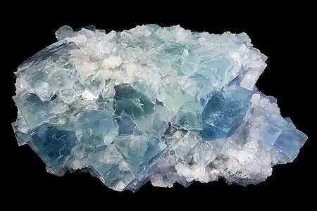 Bloc de roche cristallisée blanc à nuances bleutées ou verdâtres.