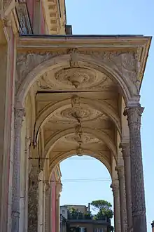 Vue du côté et du plafond du porche côté jardin. Peinture blanche très écaillée. Des morceaux de bois se détachent ou sont manquants.