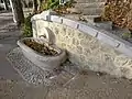 Avec son muret en pierres hexagonales, la fontaine (sans nom ?) fait office de soutènement et d'escalier vers une copropriété (2022) ;