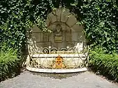  Fontaine surmontée d'un buste et entourée d’une balustrade dorée.