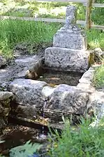 La fontaine, avec l’inscription « S PARDOUX », et, surmontant la pierre, la croix incomplète.