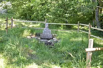 Vue générale du site de la fontaine, avec la barrière de bois protégeant le monument.