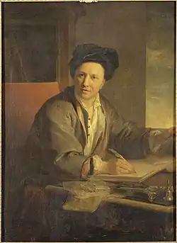 Homme coiffé d'un grand bonnet ou turban noir, écrivant assis à une table.