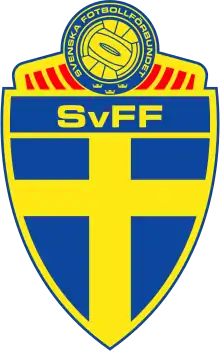 Armoiries de la Fédération suédoise. Une scandinave jaune sur fond bleu en forme de bouclier surmonté d'un ballon jaune et bleu.