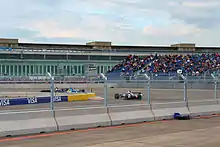 Scène de la course de Formule E de Berlin. Trois voitures sont dans un virage.